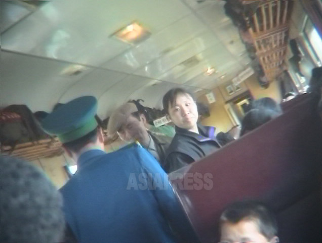 青い制服の列車保安員が乗客の検査をしている。通行証や身分証を調べる。2005年6月撮影リ・ジュン（アジアプレス）