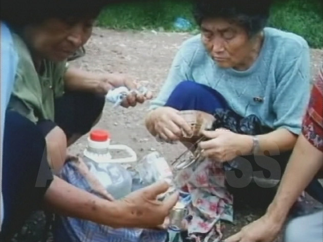 アパート街で空き瓶やペットボトルを集めるおばあさんたち。北朝鮮では廃品再利用が盛んで、少額でも現金収入になるため老人でもできる。2007年8月平壌市楽浪区域にて撮影リ・ジュン(アジアプレス) 