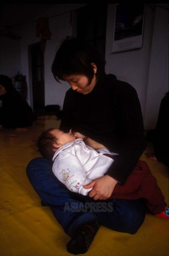 ハンミちゃんに乳をやる母のリ・ソンヒさん。 2001年1月、延辺朝鮮族自治州の隠れ家で撮影 石丸次郎（アジアプレス） 