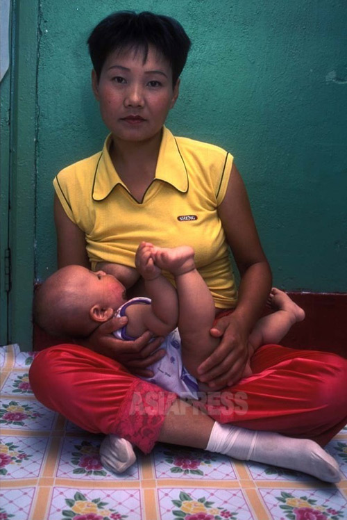 脱北難民の女性。お乳を与えているのは、保護してくれる中国の農村男性との間に生まれた女児。女性は、現在は韓国で暮らしている。1999年8月中国延辺朝鮮族自治州にて撮影石丸次郎（アジアプレス）