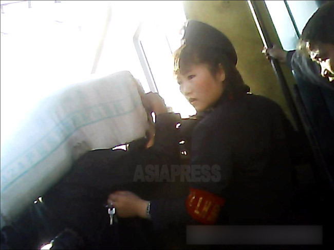 大荷物を抱えて列車に乗り込もうとする乗客を規制する女性列車案内員(車掌)。ベレー帽をかぶっている。2013年10月両江道の恵山駅にて撮影「ミンドゥルレ」(アジアプレス) 