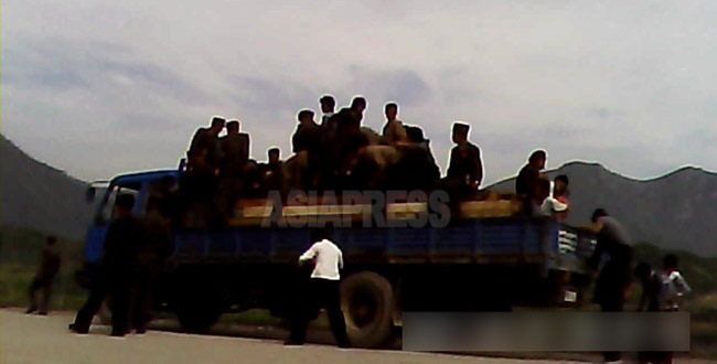 (関連写真)三水発電所の近くの検問所でトラックの荷台に乗った人々が下ろされている。 2013年8月撮影「ミンドゥルレ」(アジアプレス) 