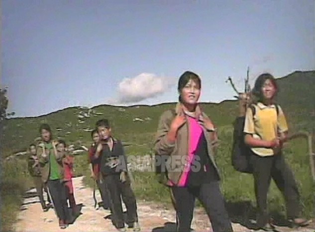 山でのドングリ集めから戻る途中の女子中生たち。「夏休み中に18キロ集めないといけない」。背嚢に薪用の木が見える。2008年8月、黄海南道の海州(ヘジュ)市郊外で撮影シム･ウィチョン(アジアプレス)
