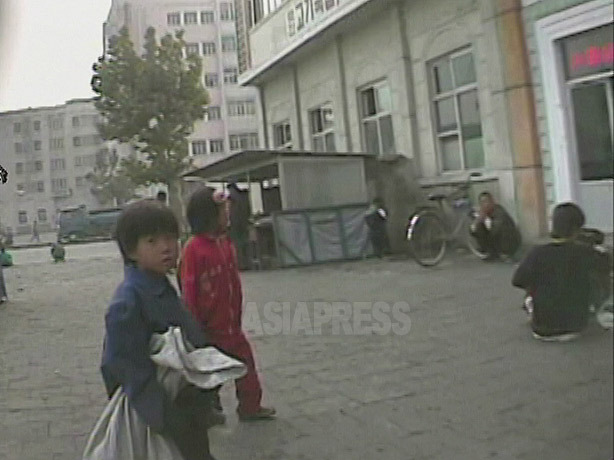 駅前の露天食堂前で物乞いする二人の幼児。右側で食事をする人を遠巻きに見つめていた。2008年10月黄海北道沙里院市にて撮影シム・ウィチョン（アジアプレス） 