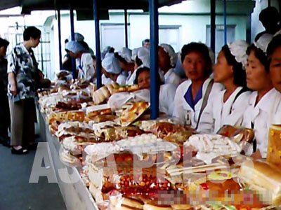 시장에서 빵이나 과자를 파는 여성들, 한 사람당 폭 80센티의 매장을 차지하고 있다. 장사에 열심이고 붙임성도 좋다. (2011년 6월 평양시 모란시장 구광호 촬영)
