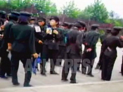 2006년 8월 평양시 서성 구역 3대 혁명 기념관 인근 광장에 김정일의 생일 축하 열병식의 훈련을 받는 여학생들이 모여 있다. 여학생들의 가슴에는 번호표가 붙어 있다. 촬영 : 리준 (아시아프레스)
