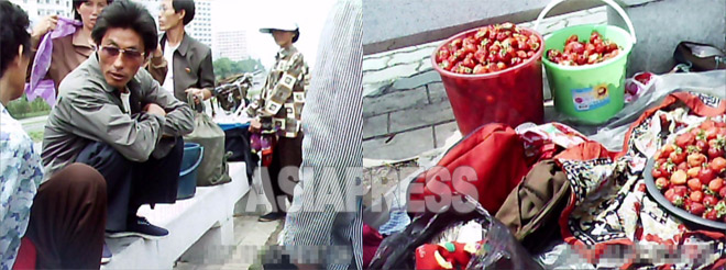 평양 중심의 대동강변에 모인 되거리꾼들. 교외에서 들어 온 딸기 가격을 도매상인과 흥정하고 있다. 2011년 7월 평양시에서. 구광호 촬영(아시아프레스)