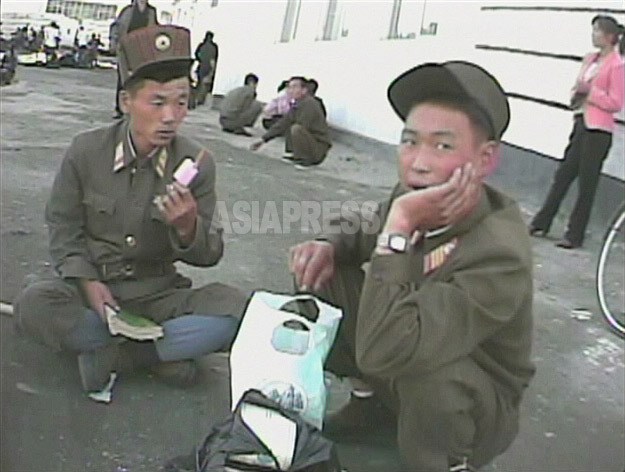 부대의 이동 도중 길에 주저앉은 병사가 먹는 것은 아이스 캔디. 장사꾼들이 자체로 만들어 판다. 2008년 9월 황해남도 해주시에서 심의천 촬영(아시아프레스)