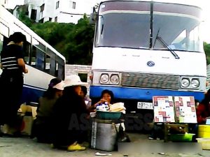 버스 승객을 대상으로 담배(오른쪽), 음식, 음료를 파는 인근의 여성들. 중국 지방도시에서 볼 수 있는 광경과 같다. 2013년 9월 평안남도 평성시에서 촬영 '민들레'(아시아프레스)