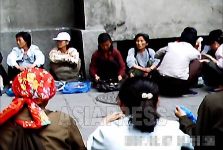 Women street vendors sitting in a line, selling goods in the area between apartment buildings. It is illegal to do this and the local authorities often made crackdowns and forcibly confiscated all goods and charged fines. But since the people's backlash was provoked, the team just patrols around and disperses them but confiscation measures are not taken these days. (Moranbong District, Pyongyang. June, 2011. Taken by Gu Gwang-ho) (C)ASIAPRESS