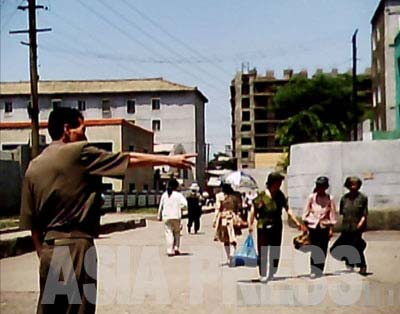 The authorities are zealous about cracking down on street side vendors. This photo shows a local municipality officer (left) driving street sellers away. In the central part of the city, they usually crack down on vendors on the main streets or near publicly-run markets, but during events that attract large numbers of foreign visitors safety officers (police) are called in to make sure no buying or selling is allowed at all even on the back streets.( June 2011, Moranbong District, By GU Gwang-ho)　ASIAPRESS 