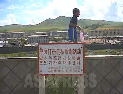 A signboard put up in Changbai County, in a town on the Chinese border upstream on the Amrok-gang(Yalu River). The signboard says "We must crack down firmly on trading of poison (drugs) and smuggling". Changbai County is across the river from Hyesan City, Ryanggang Province/North Korea, and is one of the most busy areas for smuggling. (1999 Jilin Province/China - Photo by ISHIMARU Jiro)　ASIAPRESS 