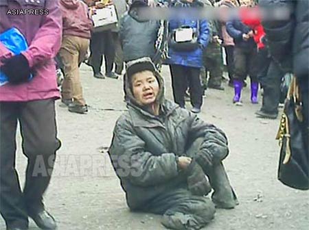 A homeless kotchebi boy sits near the entrance of the marketplace in Pyongsong, South Pyongan Province. He was begging for food and money. His legs were supposedly amputated by an accident. (March 2013) 　ASIAPRESS