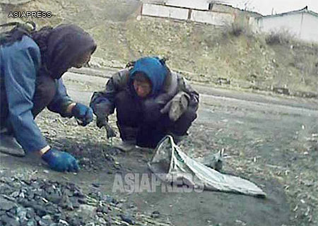 Two Women collecting coal fallen off the back of trucks. (South Pyongan Province, March 2013) ASIAPRESS