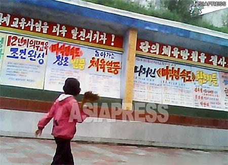A public board filled with slogans praising the implementation, by the Kim Jong-un administration, of a new system of twelve-year compulsory education. (August 2013. Photo capture from the video footage filmed in a northern city of North Korea) 　ASIAPRESS 