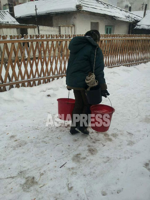 A woman returns home after fetching water from the village's public well. 2015, January. North Korean central region. (Team Mindeulle ASIAPRESS)